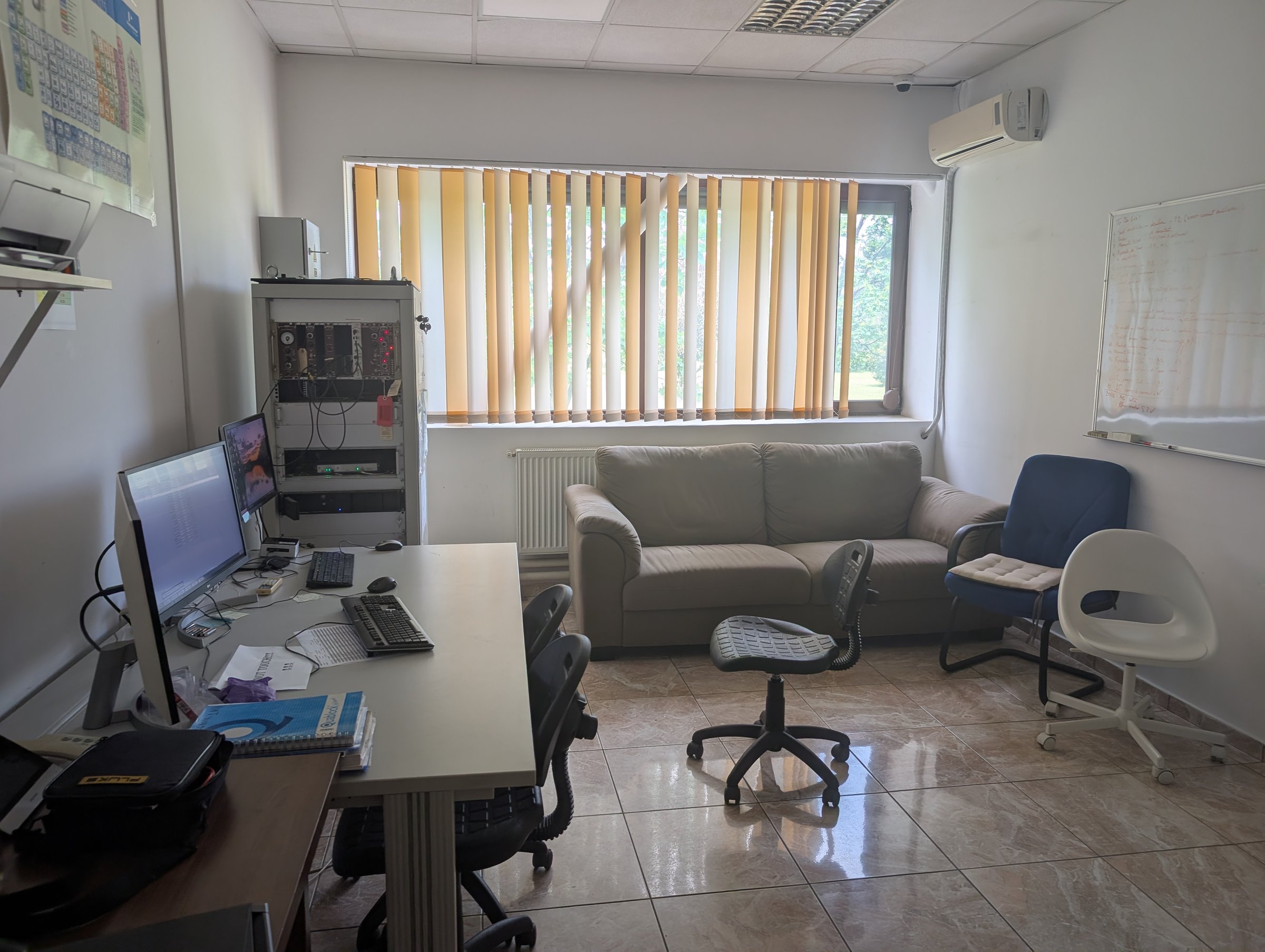 The RoAMS control room — operator workstations with dual monitors, NIM electronics rack, and meeting corner