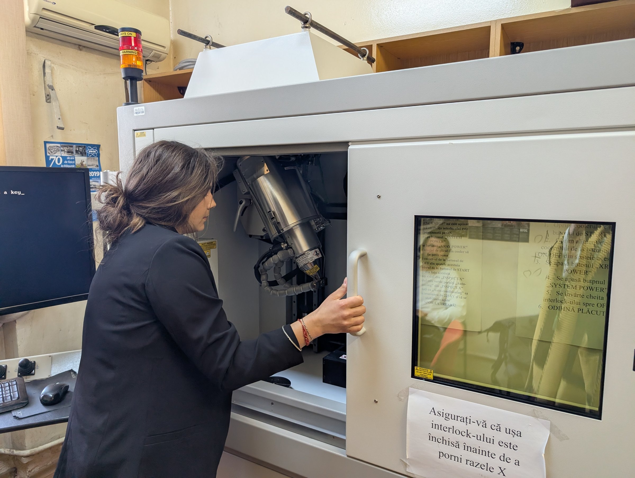 Researcher loading a sample into the Nikon XTH 225 micro-focus X-ray CT cabinet, with the micro-focus source visible inside