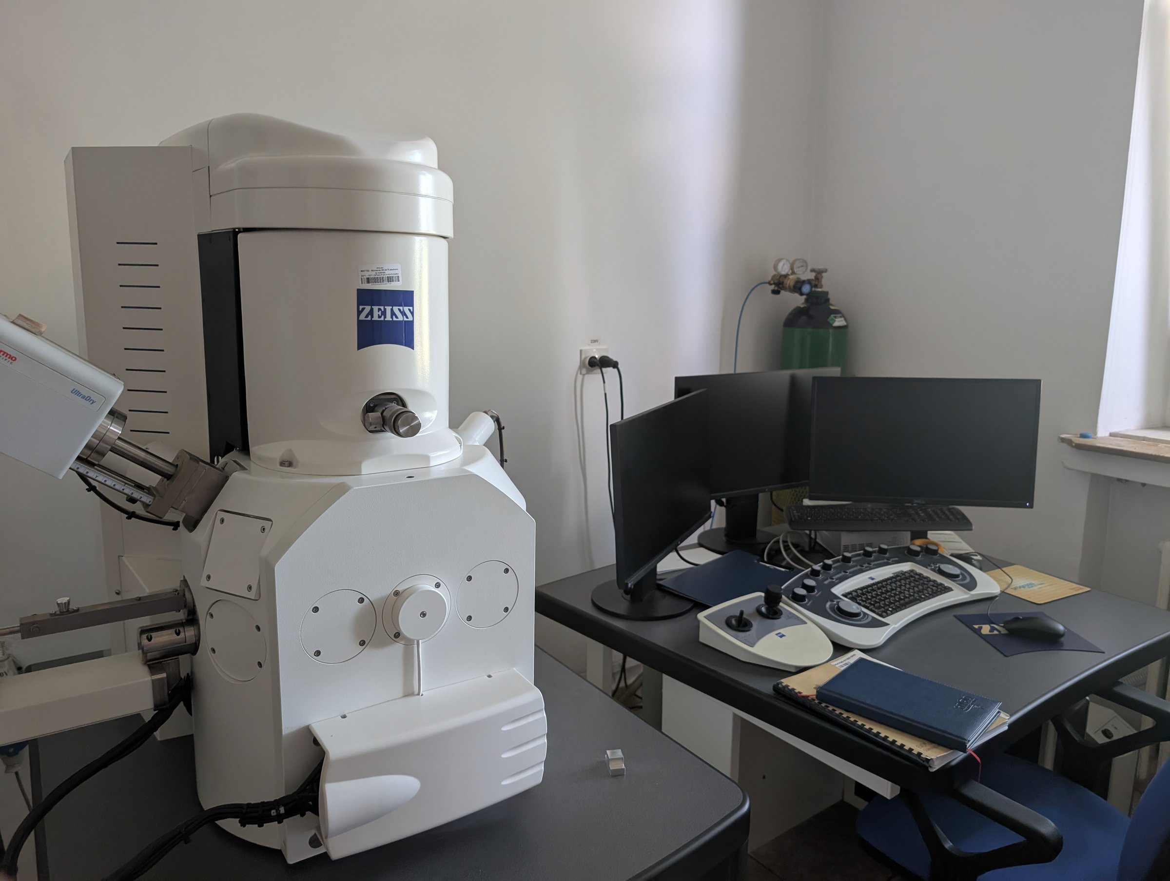 The SEM sample-preparation bench with a stereo microscope, mounting stubs, tweezers and aluminium foil