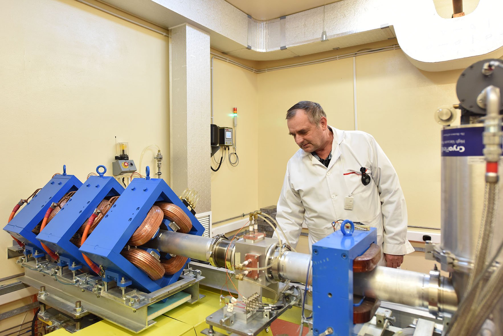 A DFNA engineer at the TR-19 external beamline, beside the quadrupole focusing magnets that steer extracted protons toward the experimental stations