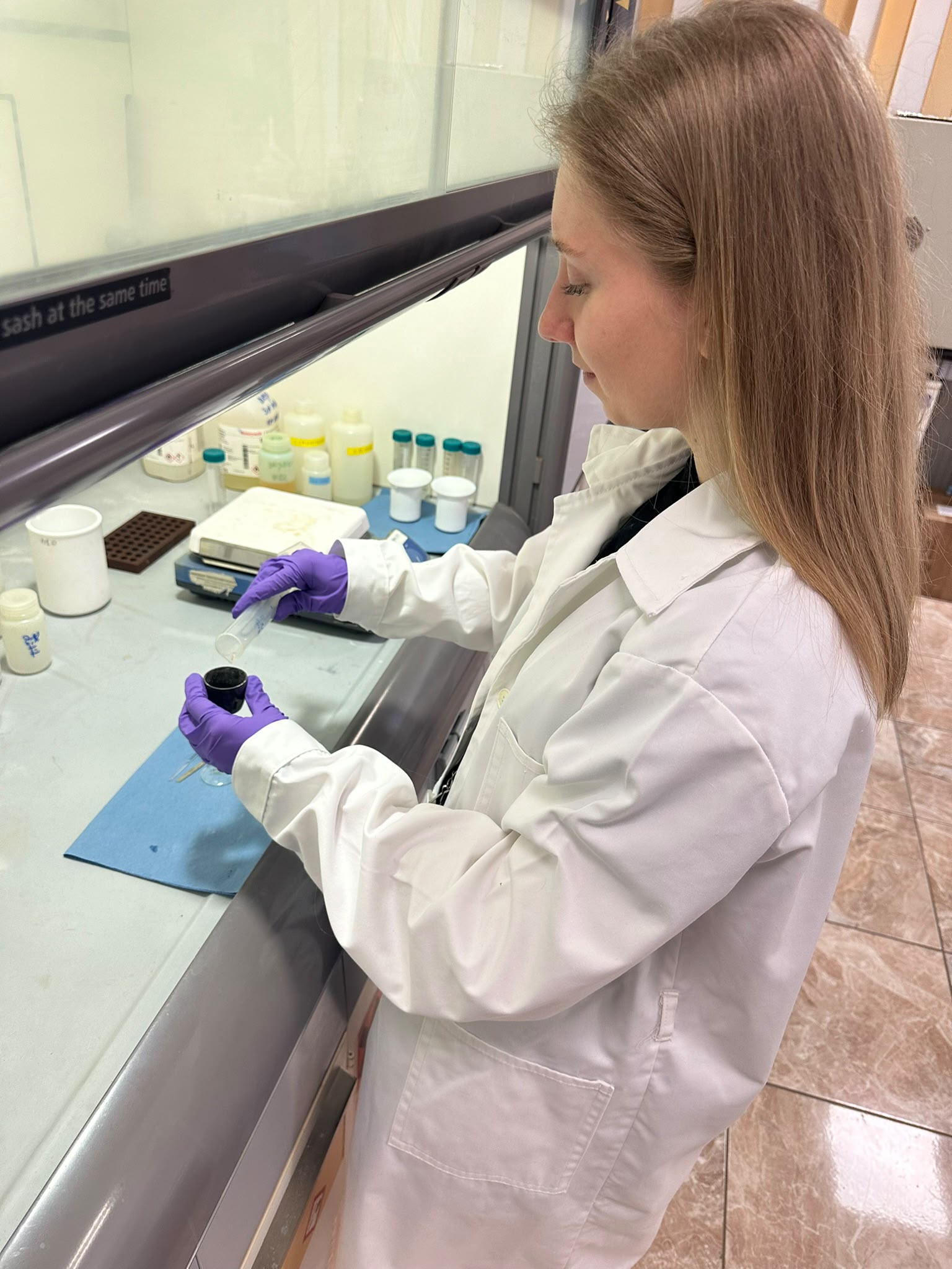 Researcher transferring a prepared sample into a cathode under the fume hood for AMS measurement