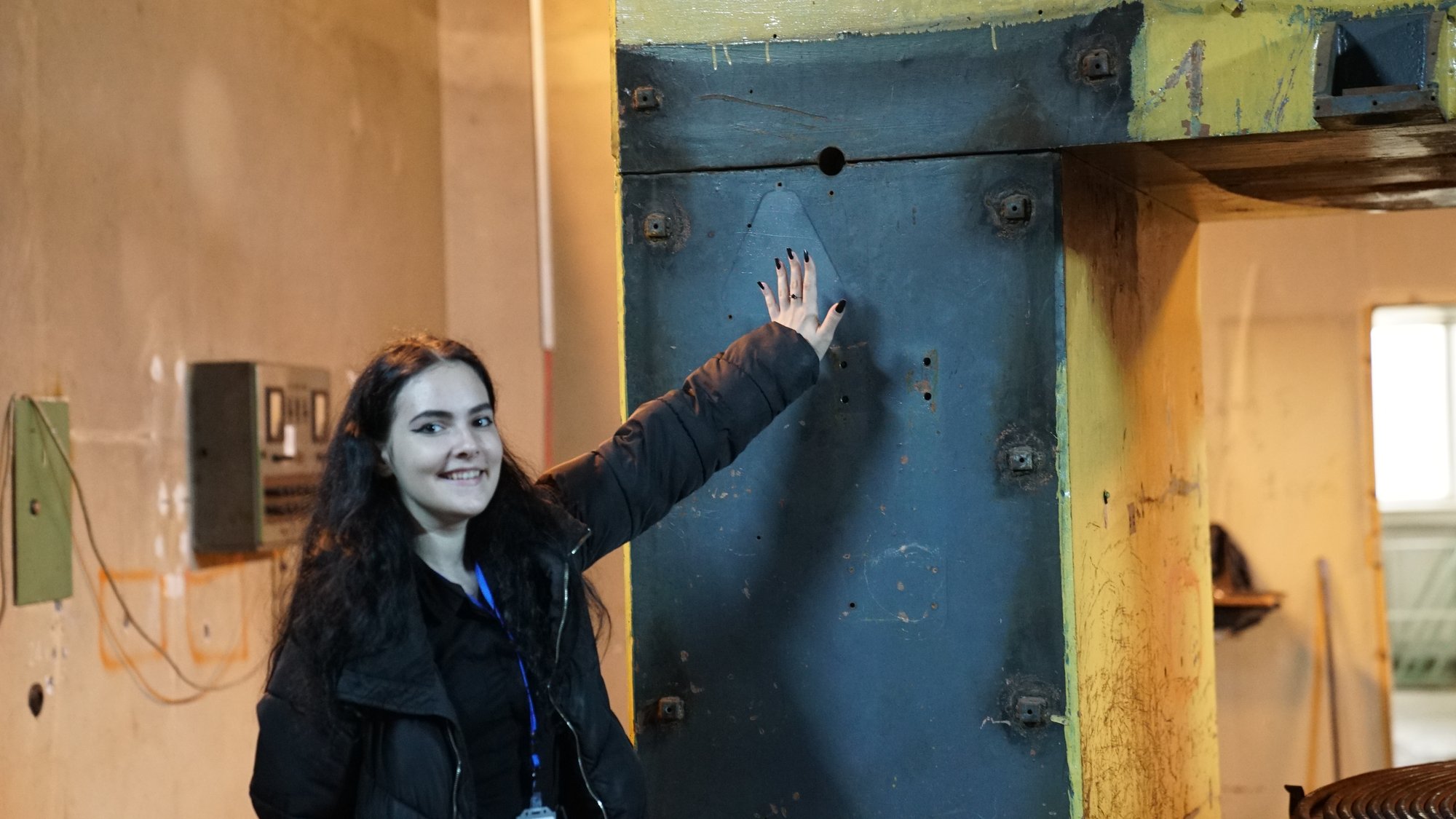 A trainee poses cheerfully beside the industrial press equipment at IRASM