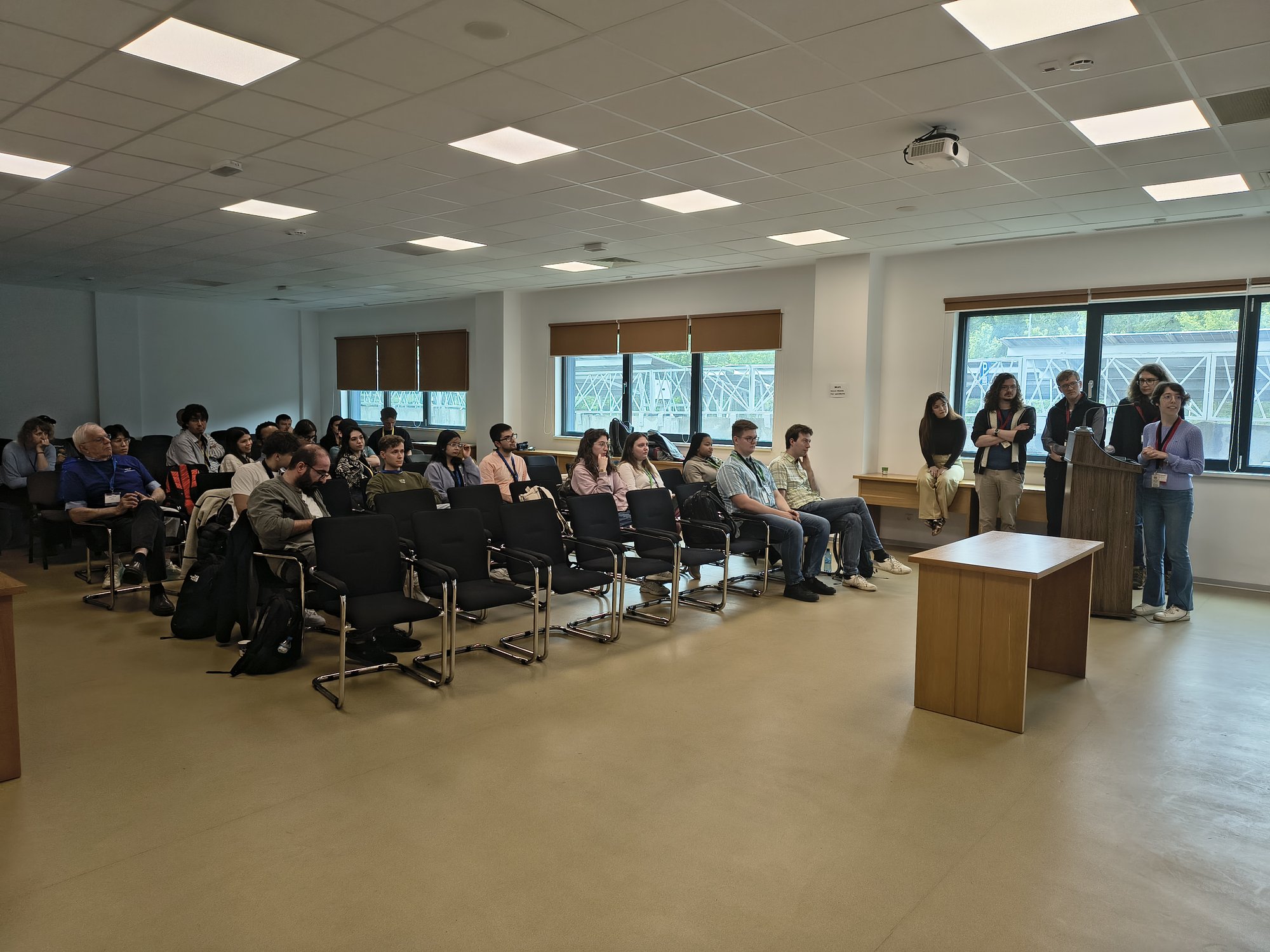 A full lecture room listens to a presentation from the podium