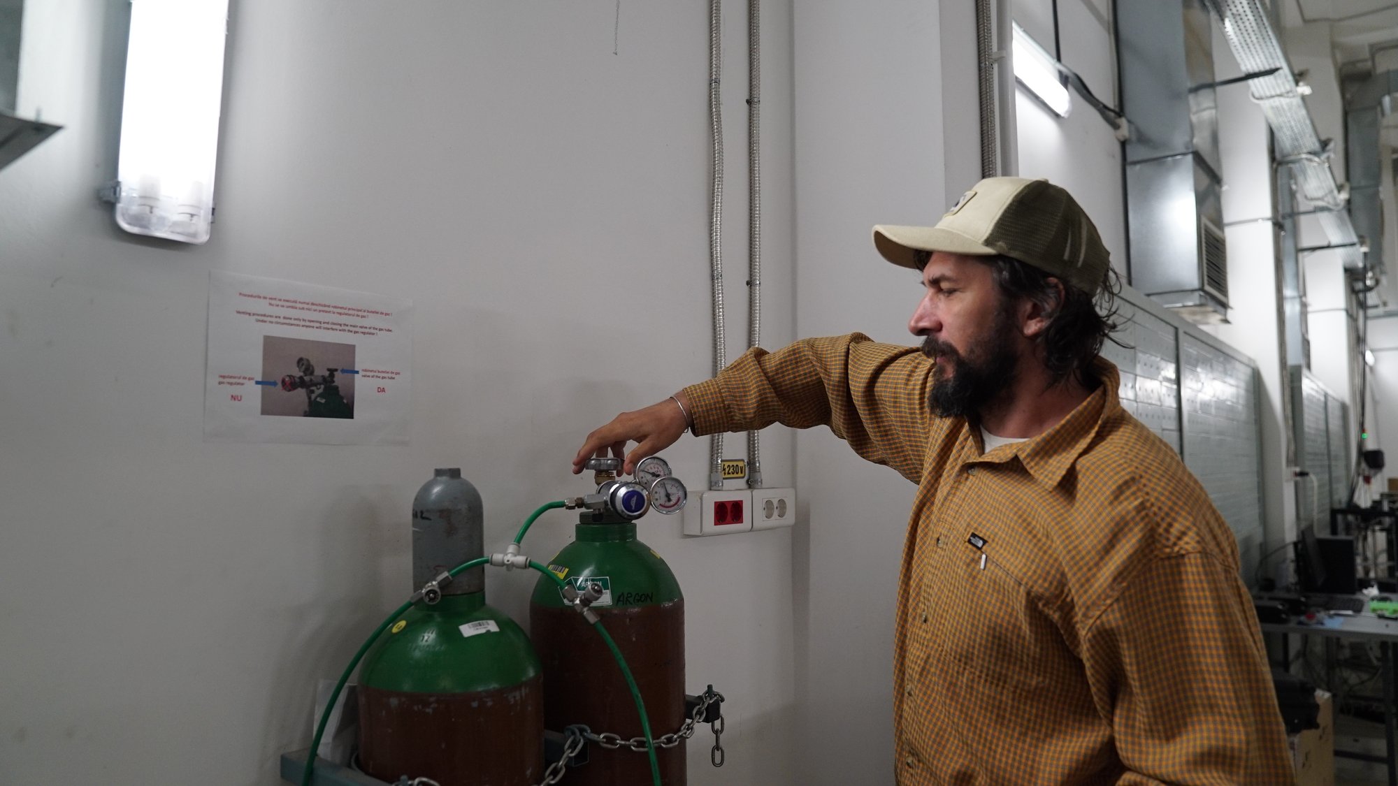 A trainer demonstrates high-vacuum gas cylinders and regulators in the target-preparation workshop