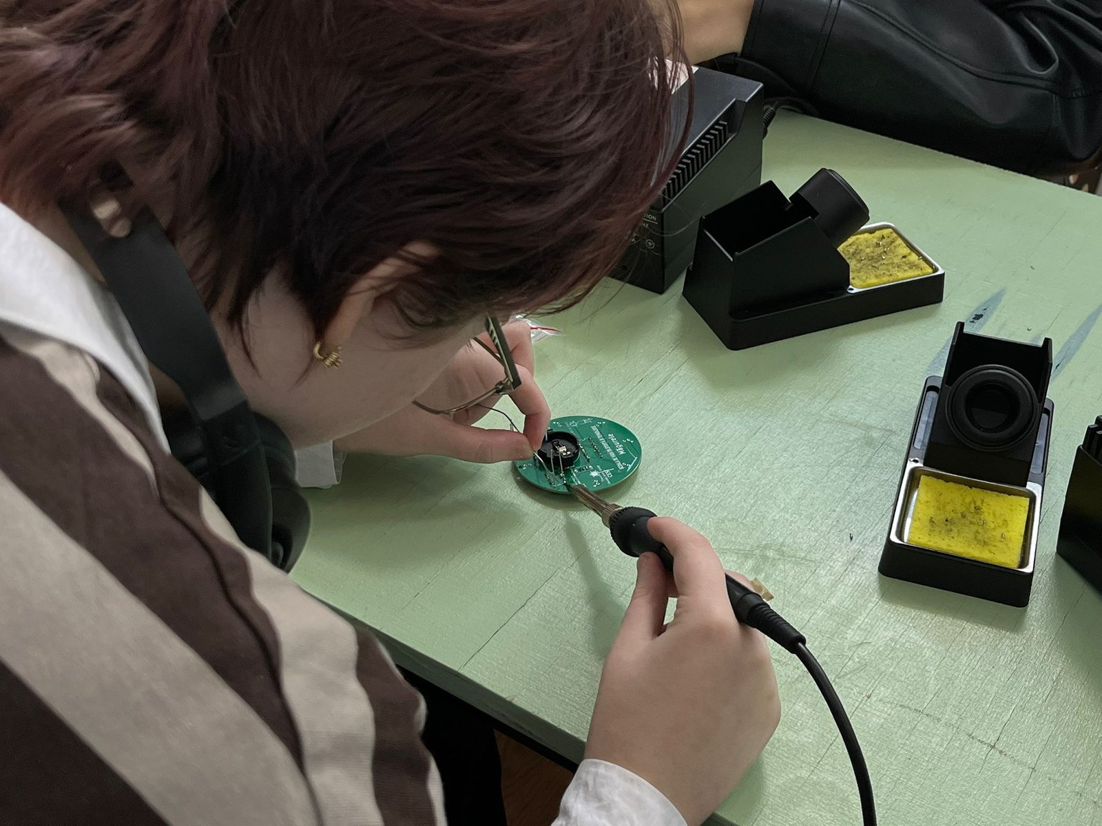 A student soldering a small electronic kit at a hands-on DFNA workshop