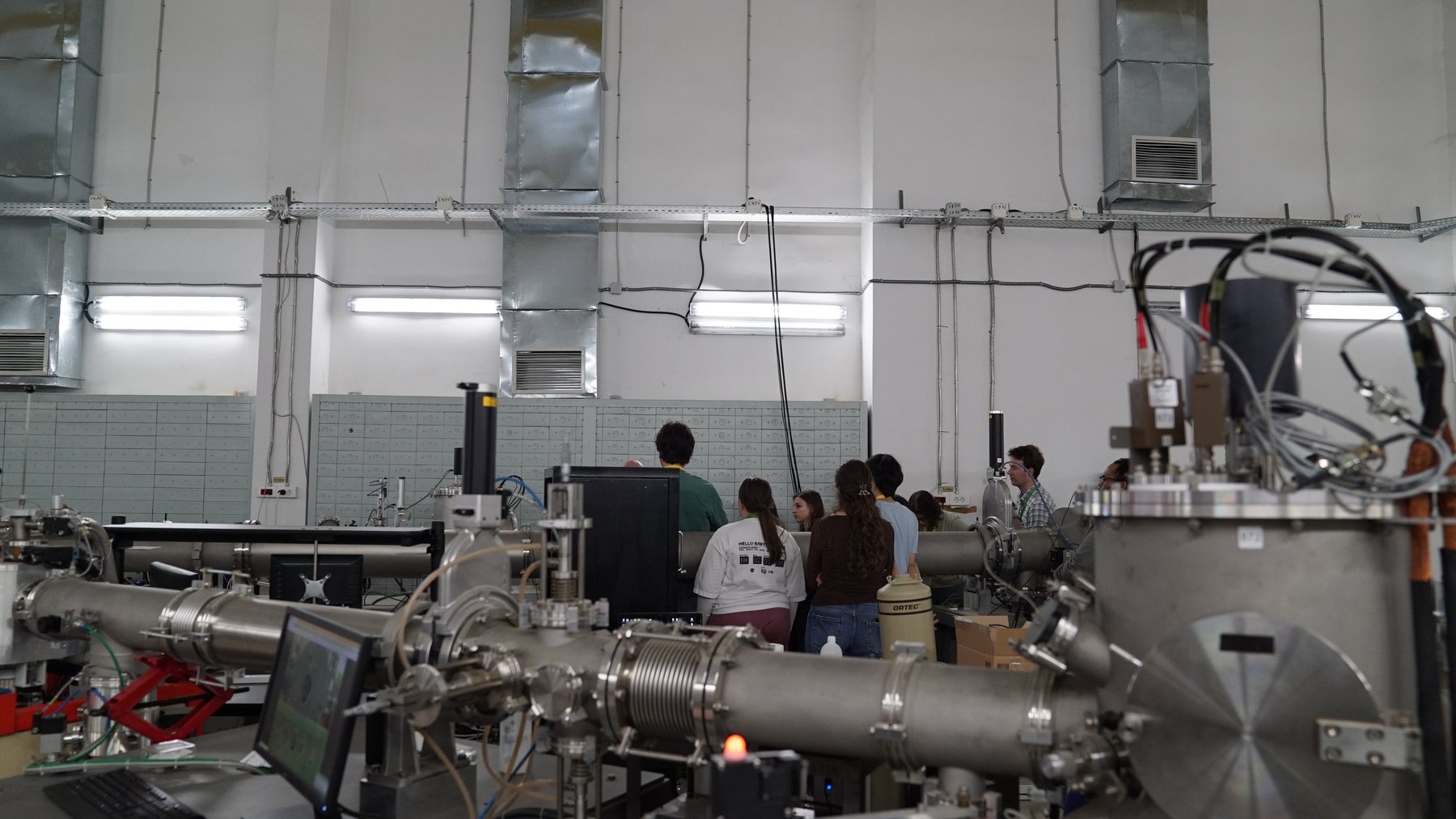 Students touring the accelerator hall, gathered around a beamline during an open day