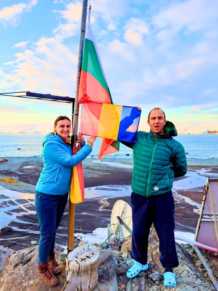 Daniela Pascal and a colleague from the Bulgarian expedition holding the Romanian and Bulgarian flags at the base, with the sea behind them