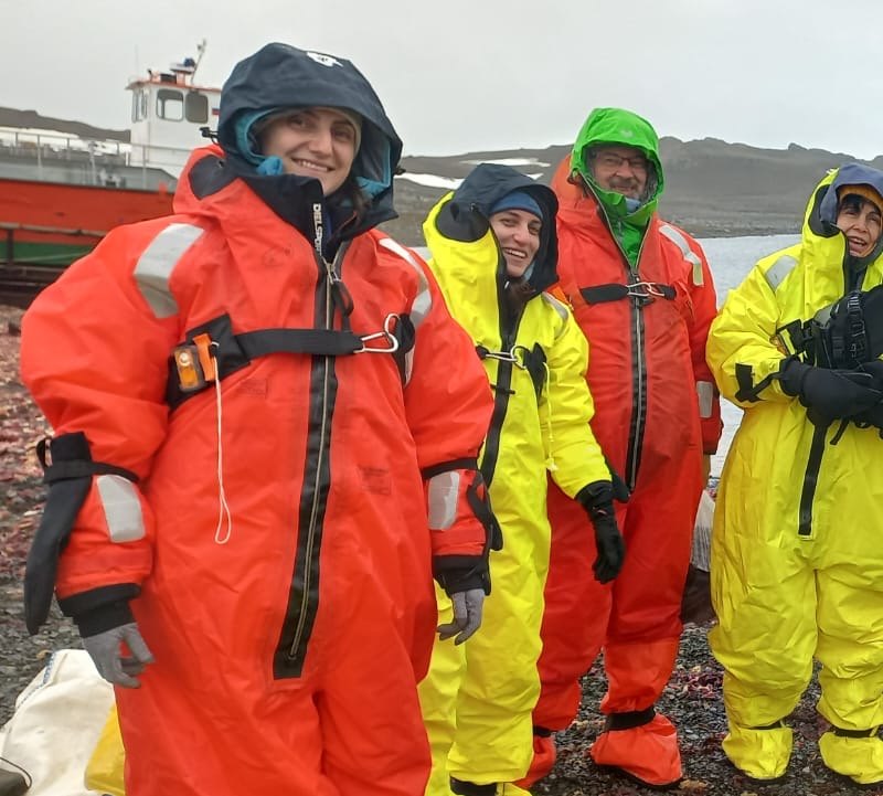Daniela Pascal with members of the Bulgarian expedition in bright orange and yellow survival suits on the shore