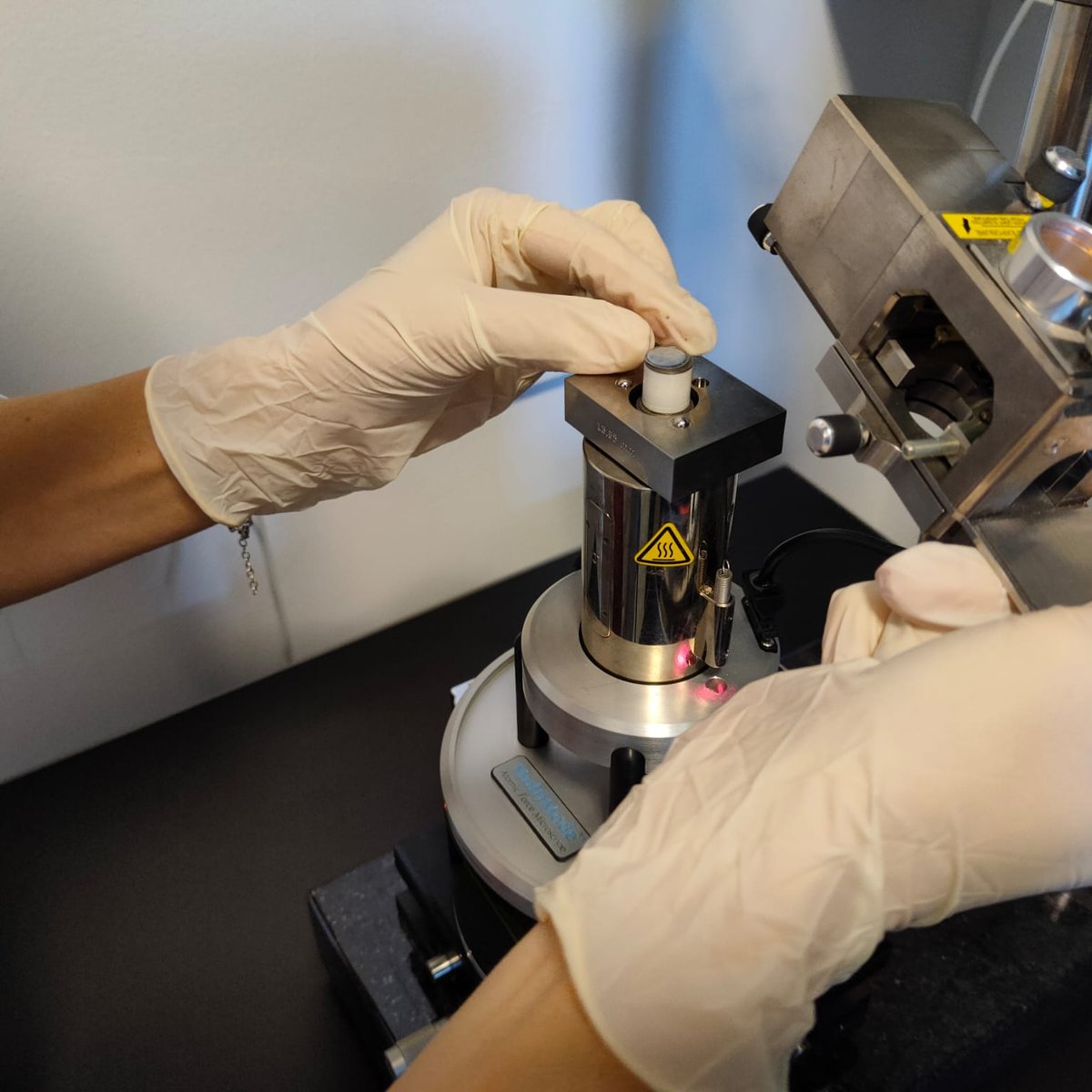 A researcher loading a sample onto the AFM stage in the NANOMAT laboratory — matter characterisation and radiation testing