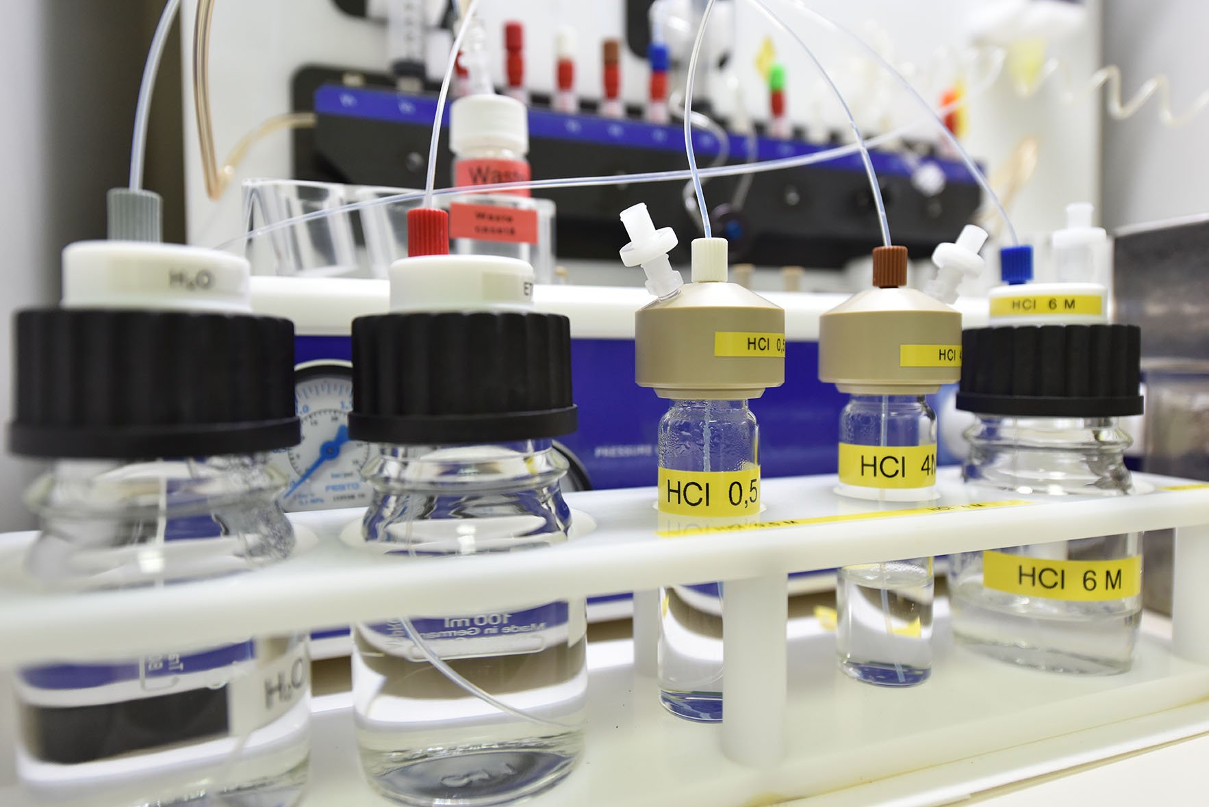 Labelled reagent vials (H2O, HCl 0.5 M, 4 M, 6 M) plumbed into an automated radiochemistry module