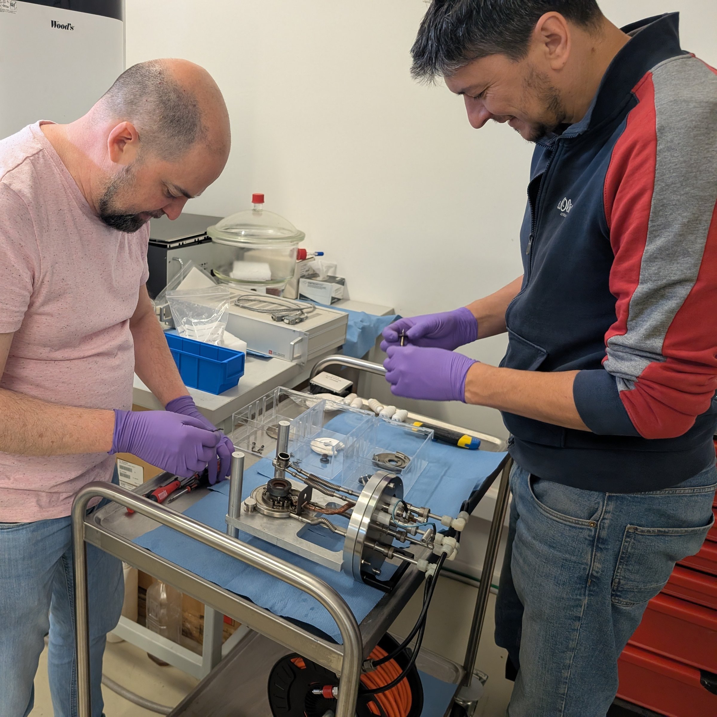 Two DFNA researchers assembling an ion source component of the RoAMS AMS system
