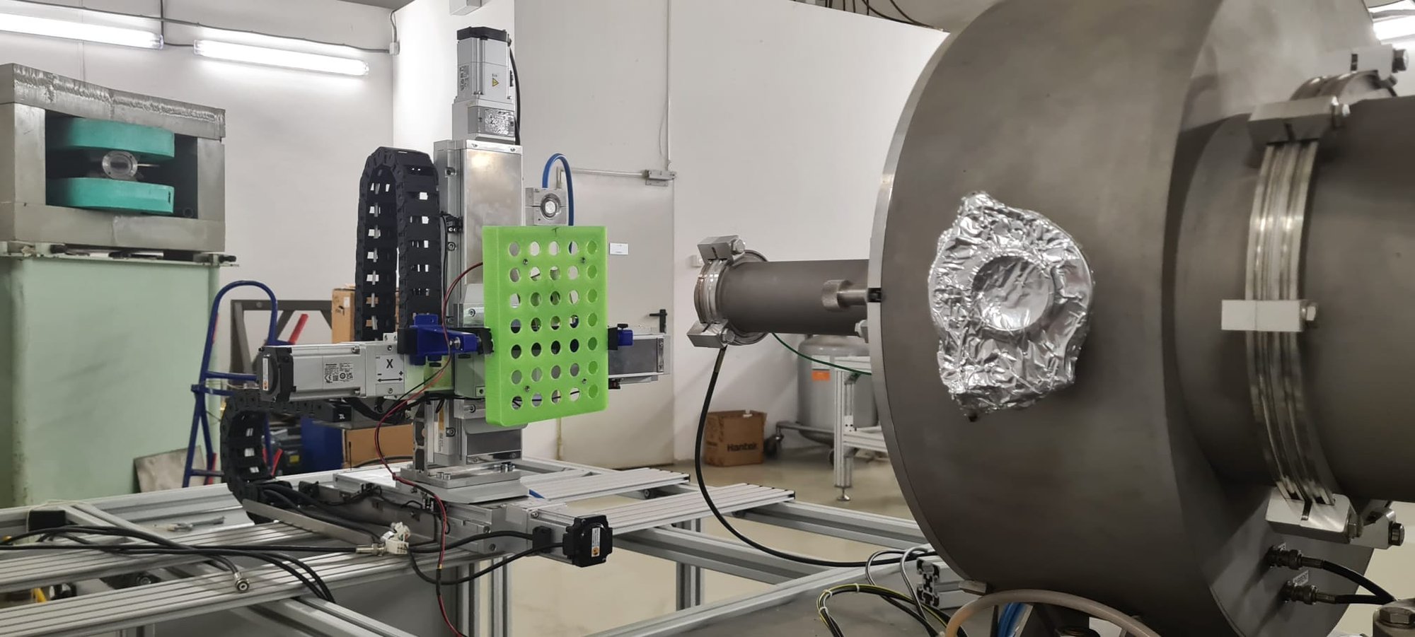 The green multi-aperture sample holder on the XYZ stage facing the beam extraction nozzle